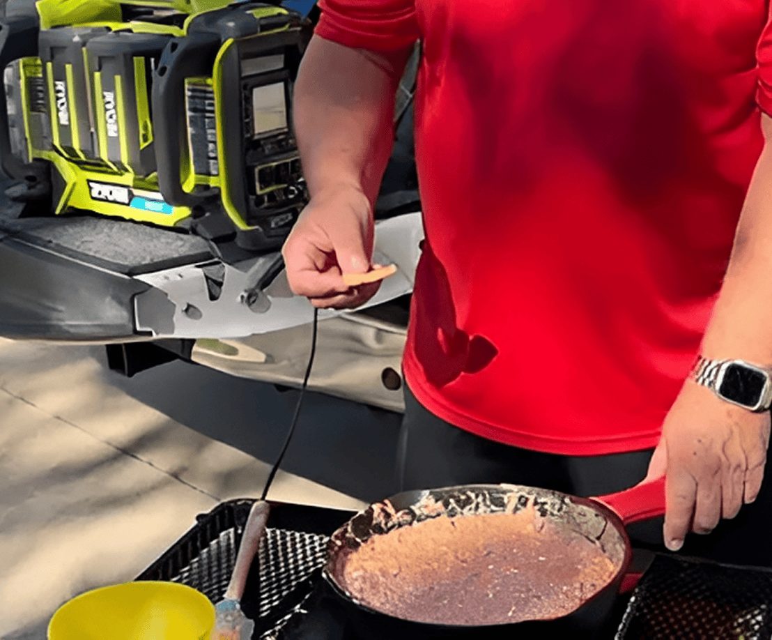 Person cooking outdoors with portable power station.