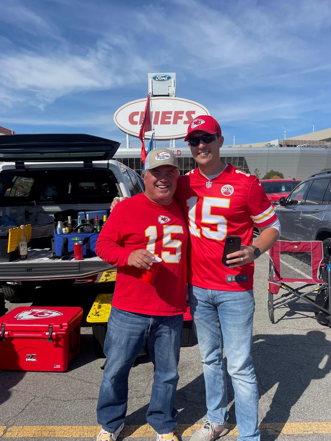 Two fans in red jerseys tailgating.