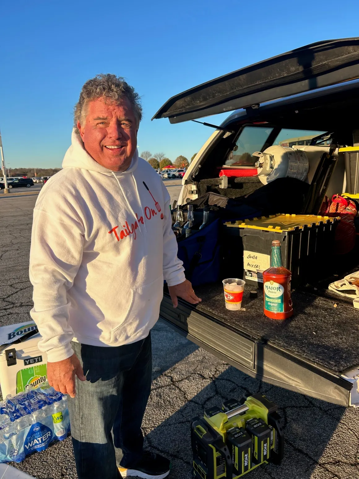 Man smiling by open car trunk tailgating.