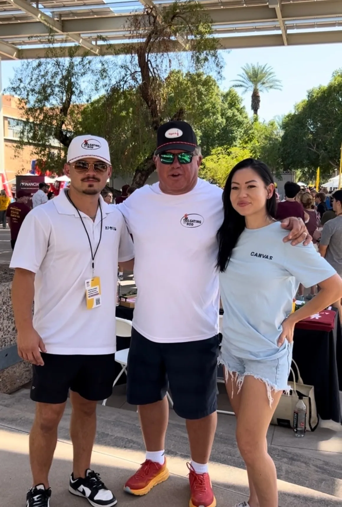 Three people posing outdoors at event.