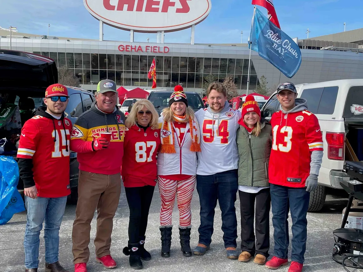 Fans tailgating at football stadium parking lot.
