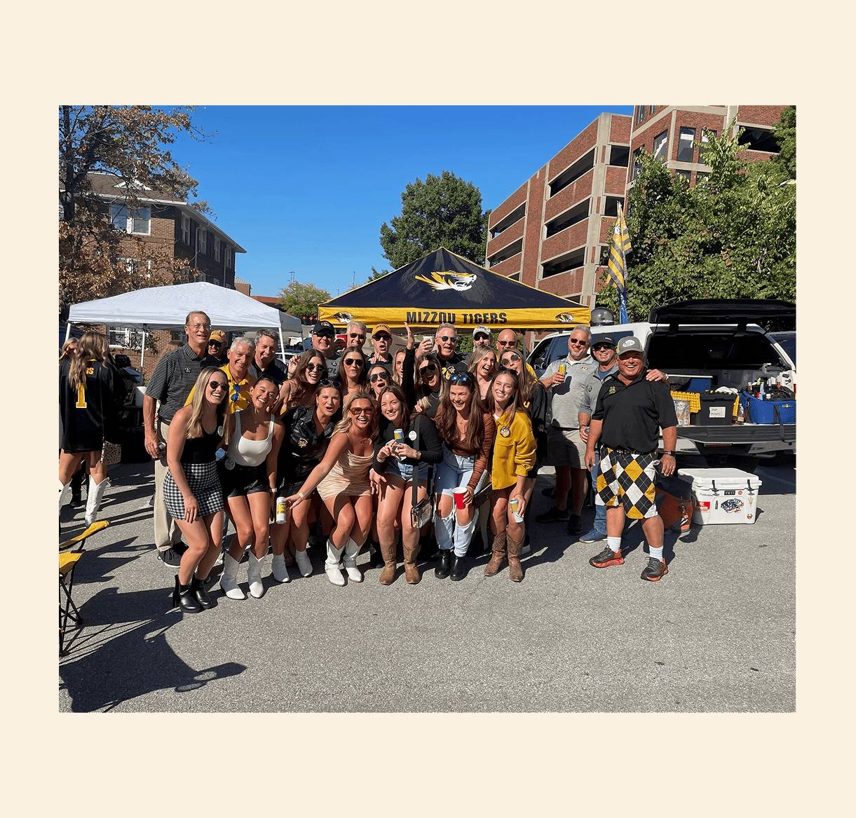 Group posing at outdoor tailgate event.